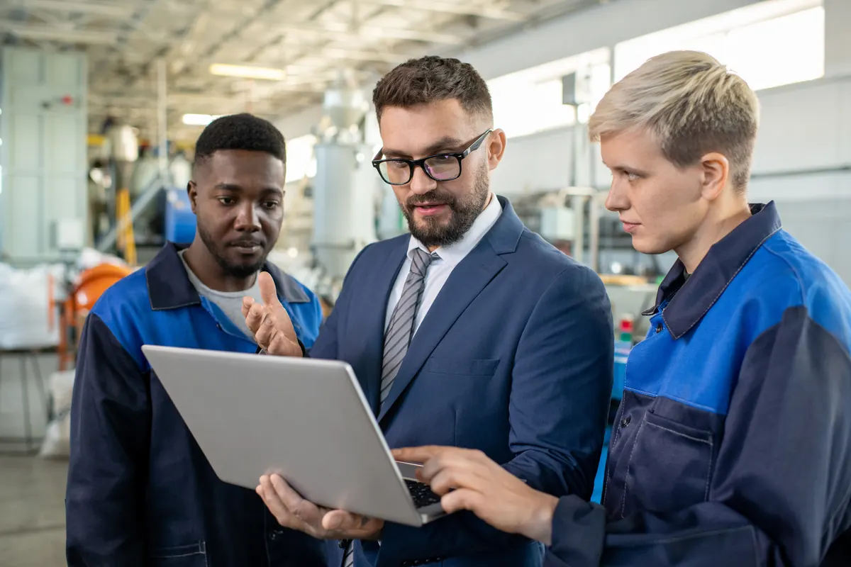 Responsable et techniciens d'atelier comparant un plan et la pièce